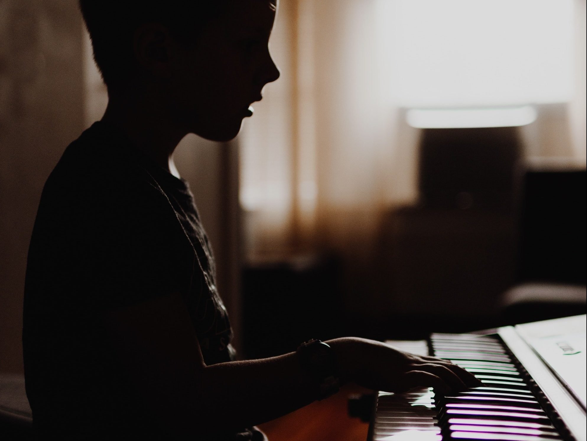 Boy playing piano in room